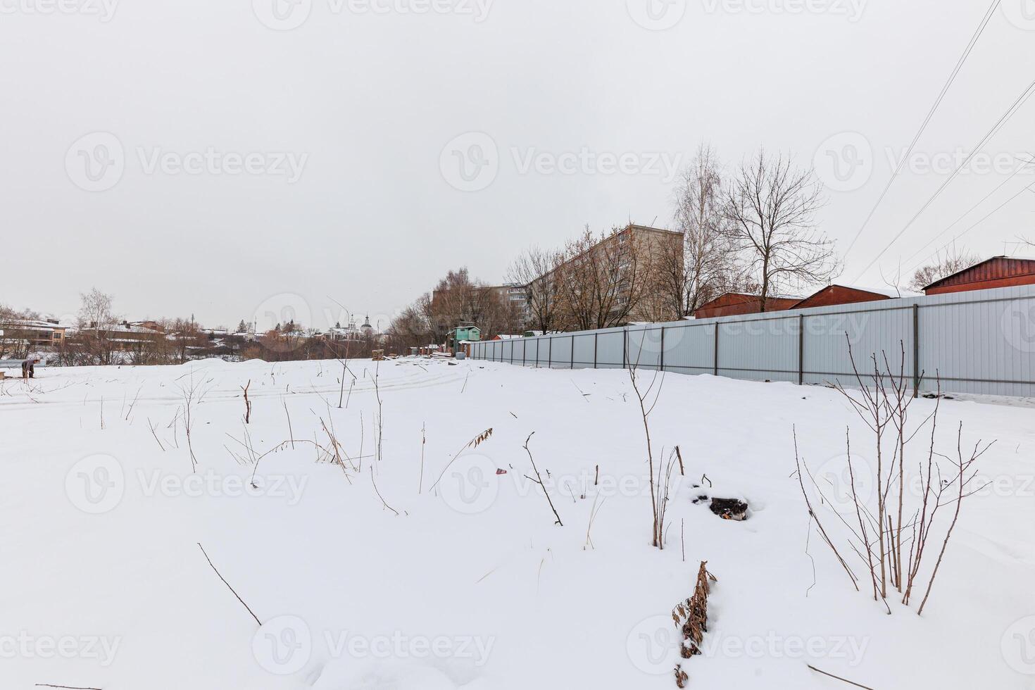 Whispers of Winter A Tranquil Snow-Kissed Landscape Framed by Bare Trees and Fenced Reflections of Urban Life. photo