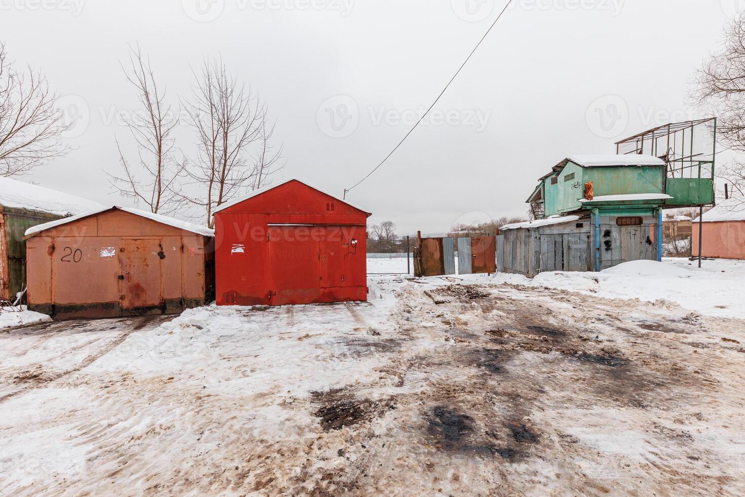 Whispers of Winter A Solitary Row of Garages Enveloped in Snow, Beside a Forgotten Rusted Structure. photo