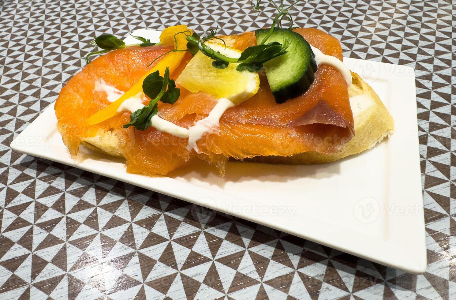 Delicious smoked salmon open sandwich with cucumber and lemon garnish photo