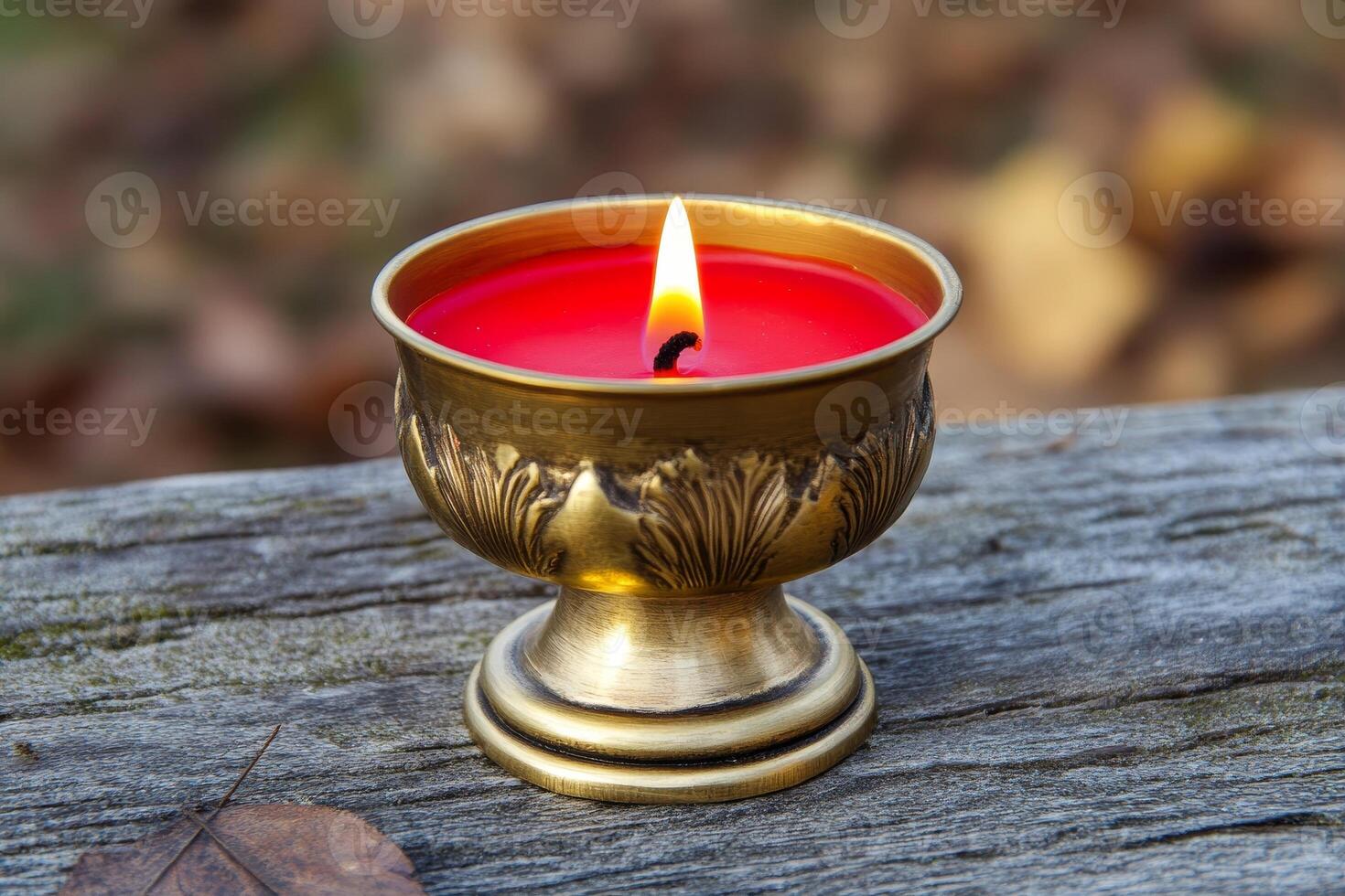 Red candle in an elegant golden candlestick on a wooden surface photo
