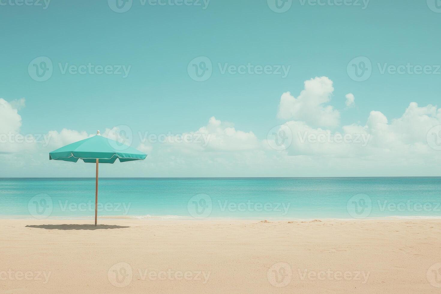 Beach umbrella in turquoise color standing on sand under clear sky photo