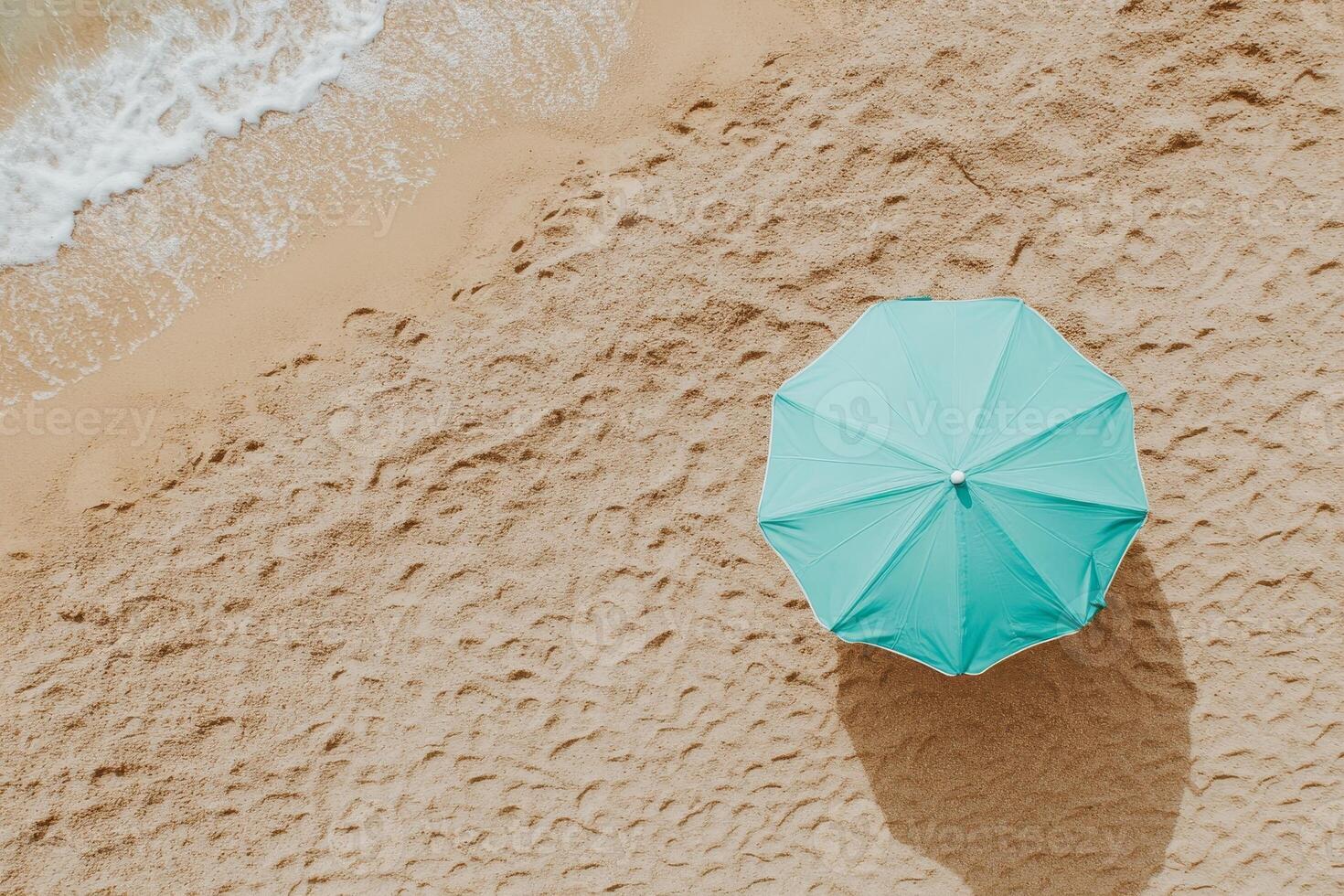 Beach umbrella in turquoise color on brown sand under clear sky photo