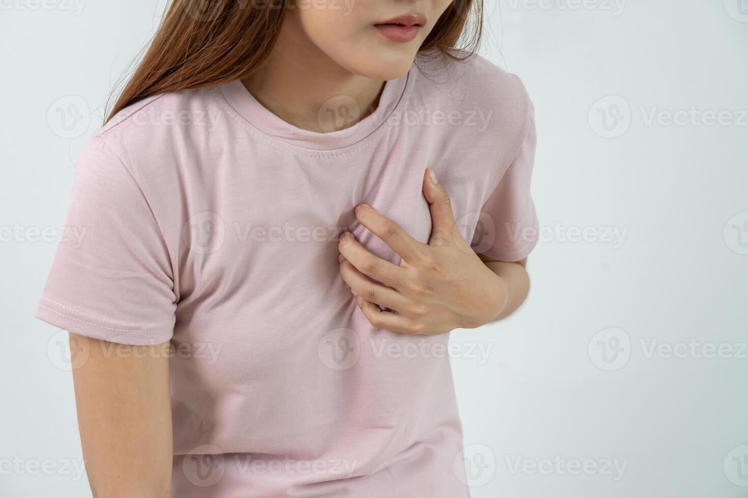 hand hold chest with heart attack symptoms, asian woman working hard have chest pain caused by heart disease, leak, dilatation, enlarged coronary heart, press on the chest with painful expression. photo