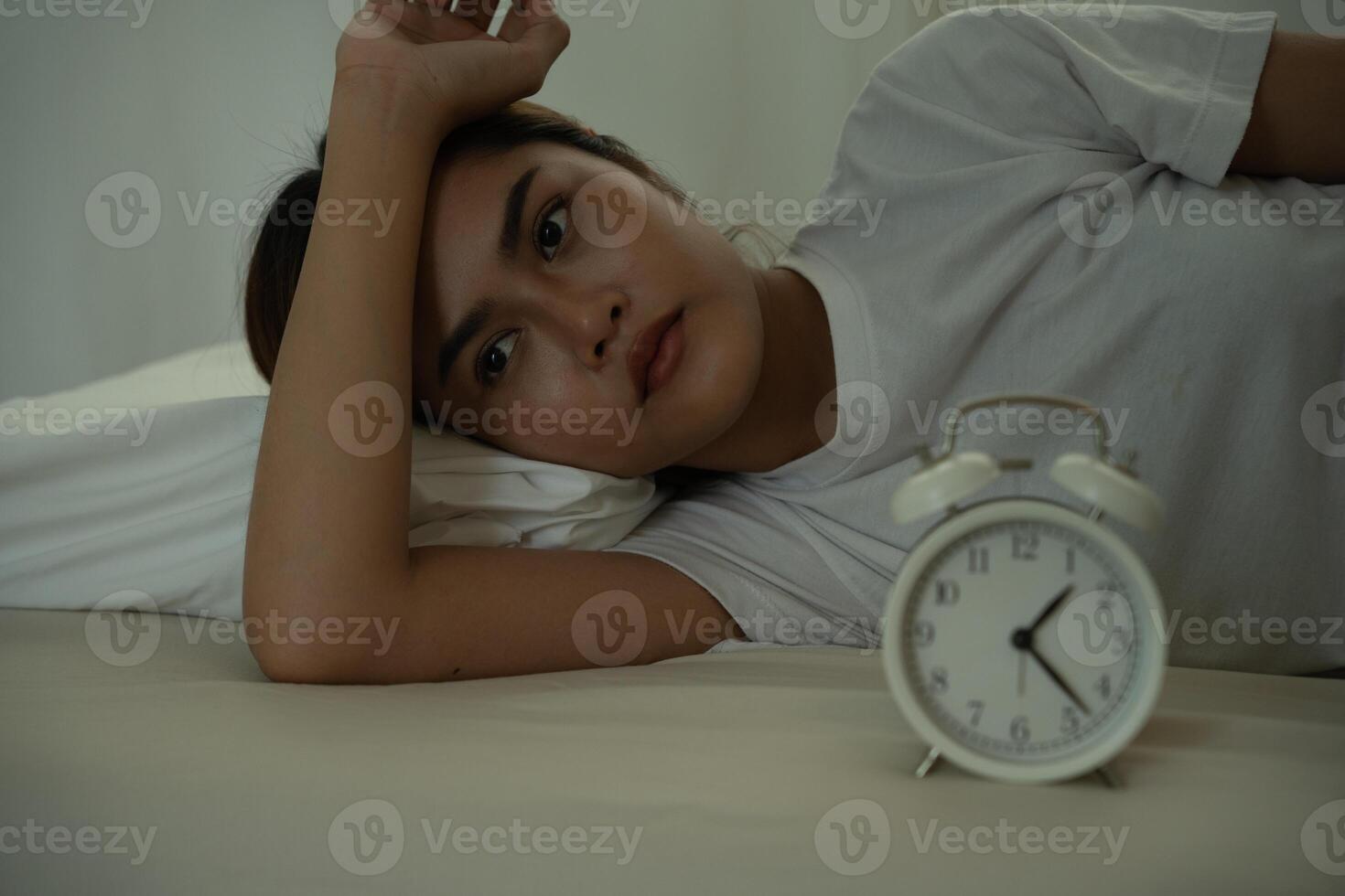 female in bed late trying to sleep suffering insomnia, sleepless or scared in a nightmare, looking sad worried and stressed. Tired and headache or migraine waking up in the middle of the night. photo