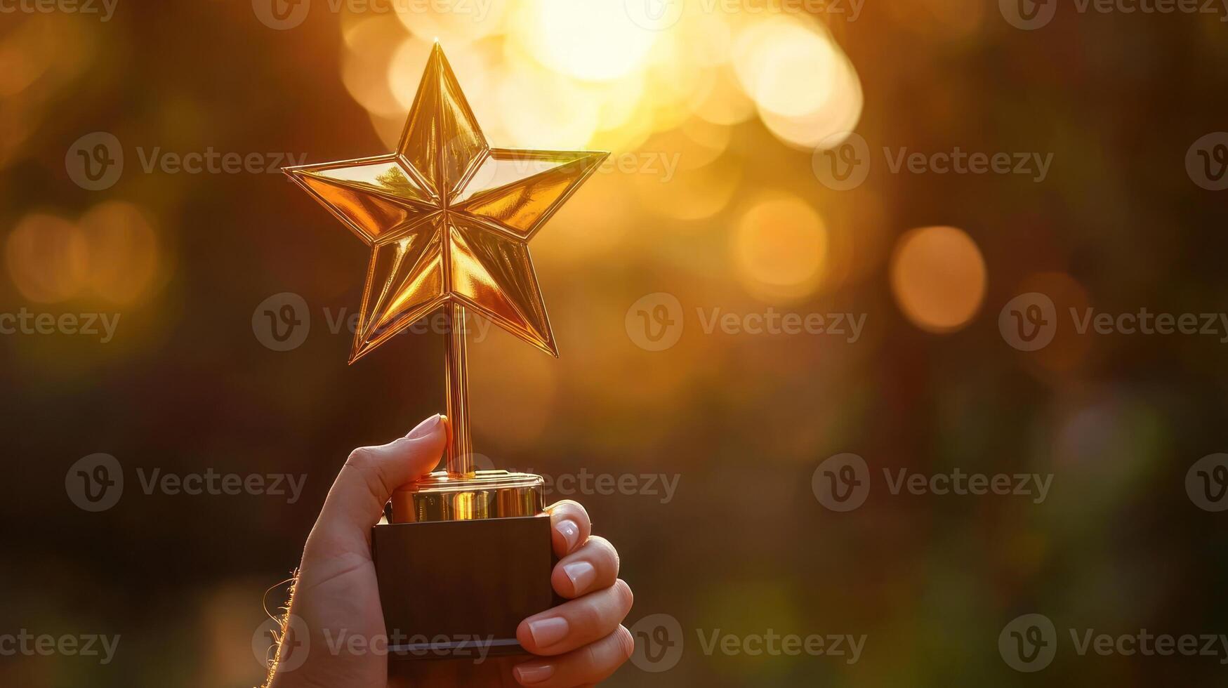 hand holding golden star trophy against blurred sunset background, symbolizing achievement and recognition photo