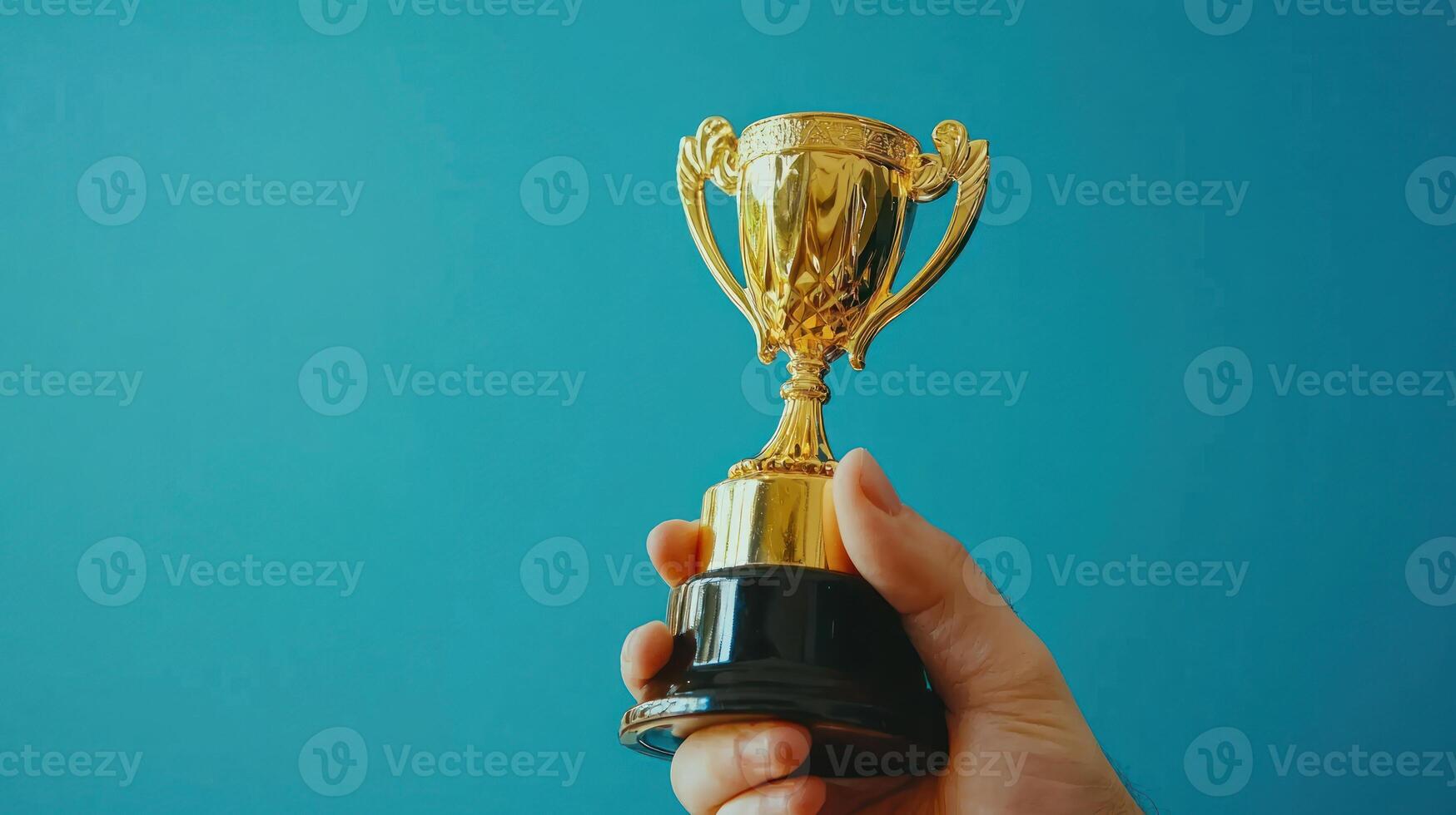 person holding golden trophy against blue background, symbolizing achievement and success photo
