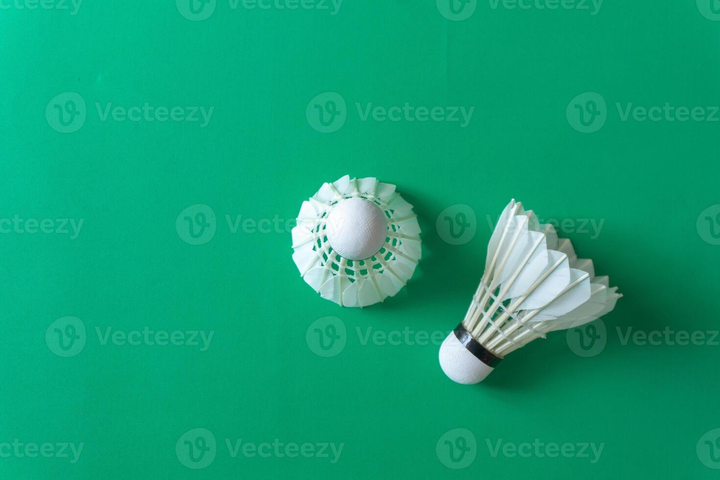 Two shuttlecocks against a vivid green surface, ideal for creative layouts photo