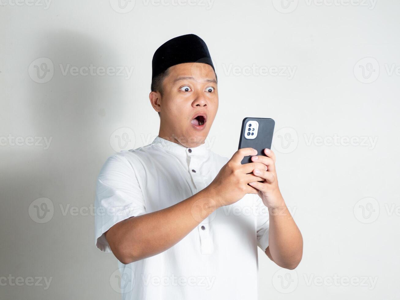 Muslim Asian man shows shocked and surprised expression while his mobile phone photo