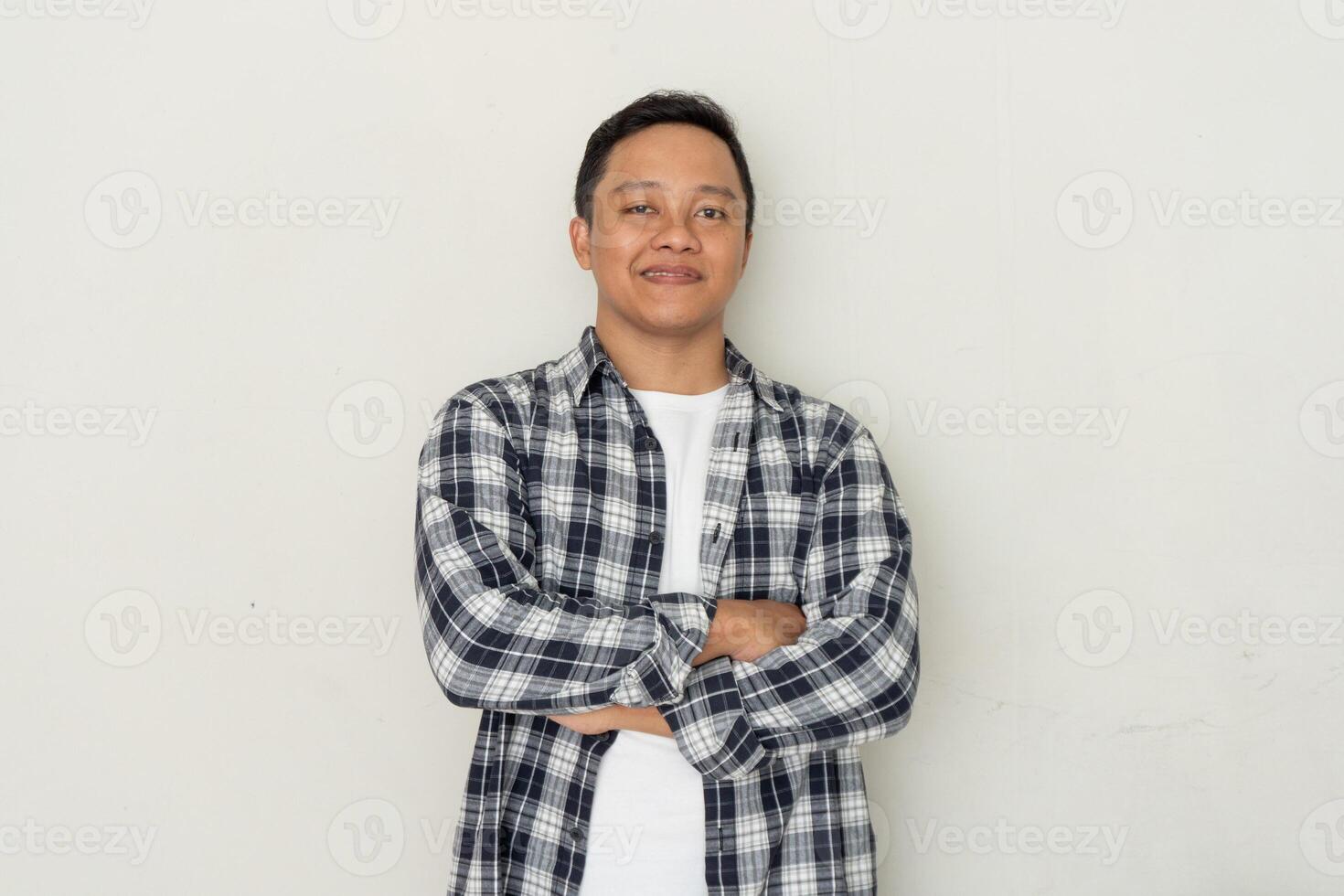 Smiling handsome Asian man standing with crossed arms isolated on white background. photo
