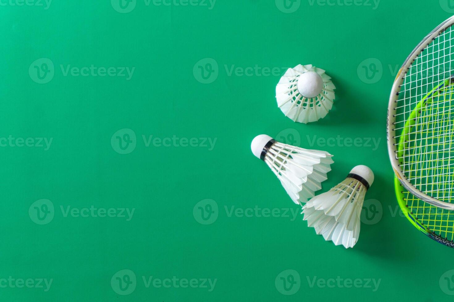 Flat lay of badminton rackets and shuttlecocks on a vibrant green surface. photo