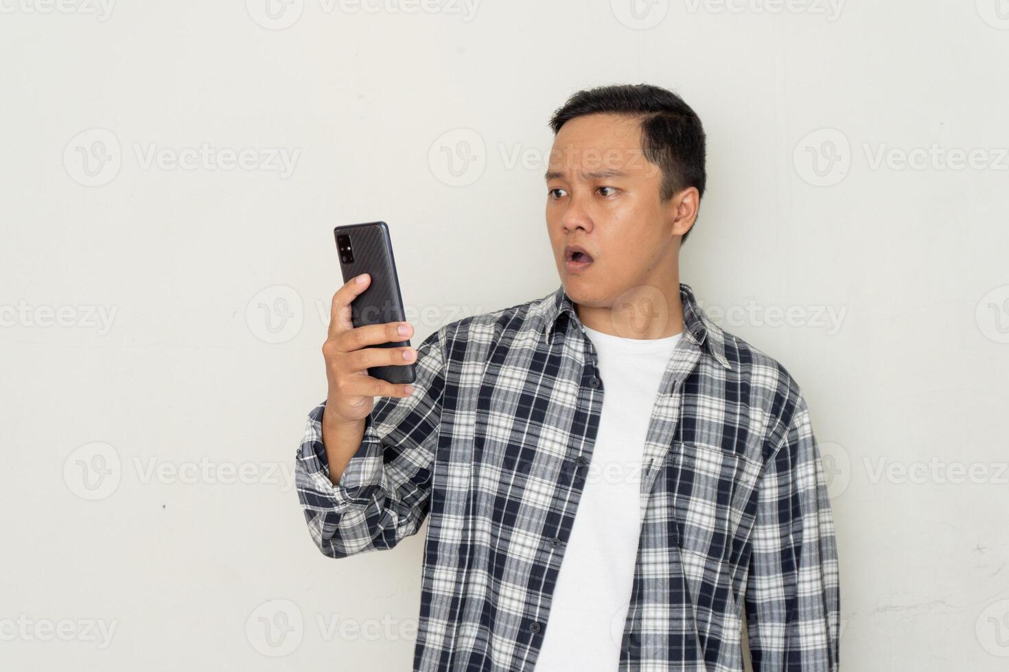 Asian man pointing to mobile phone with afraid and surprised expression. Promotion cocept photo
