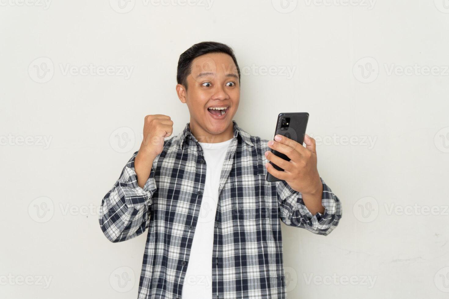 man happy and excited while looking to his phone. Young man surprised and shocked looking to handphone photo