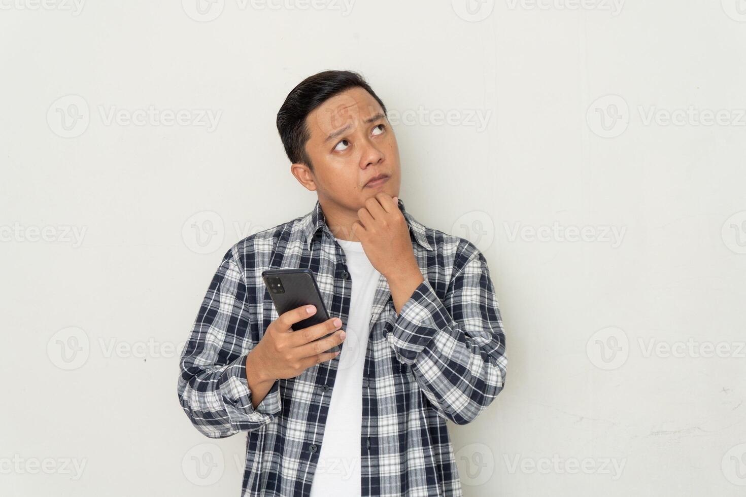 Asian man thinking and concentrating while holding handphone. photo