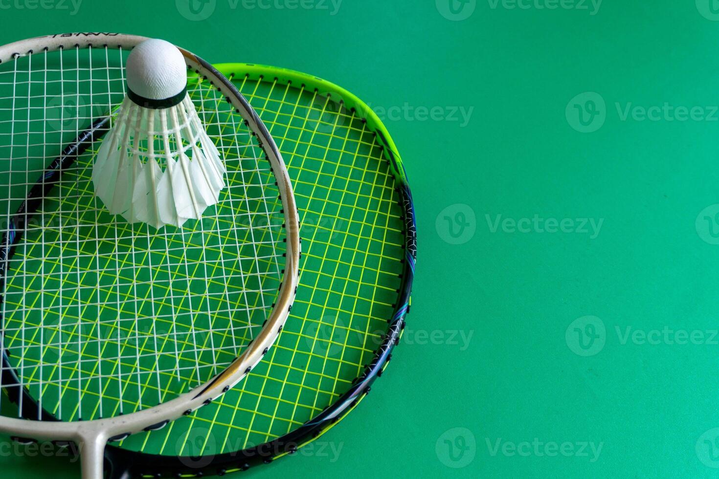 Two badminton rackets and a shuttlecock over green background. Badminton sport concept photo