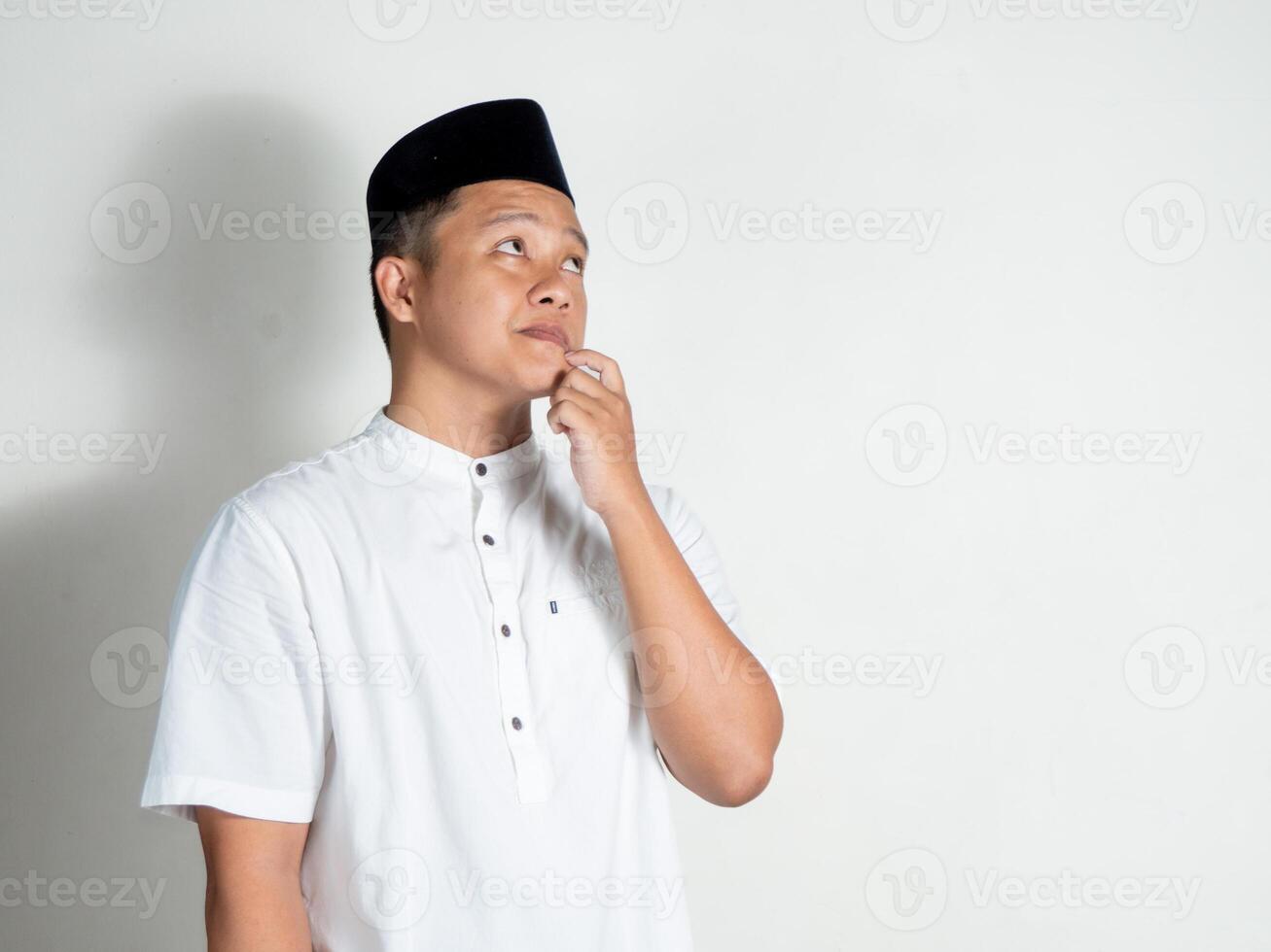 Moslem Asian man thinking and concentrating while holding his chin photo