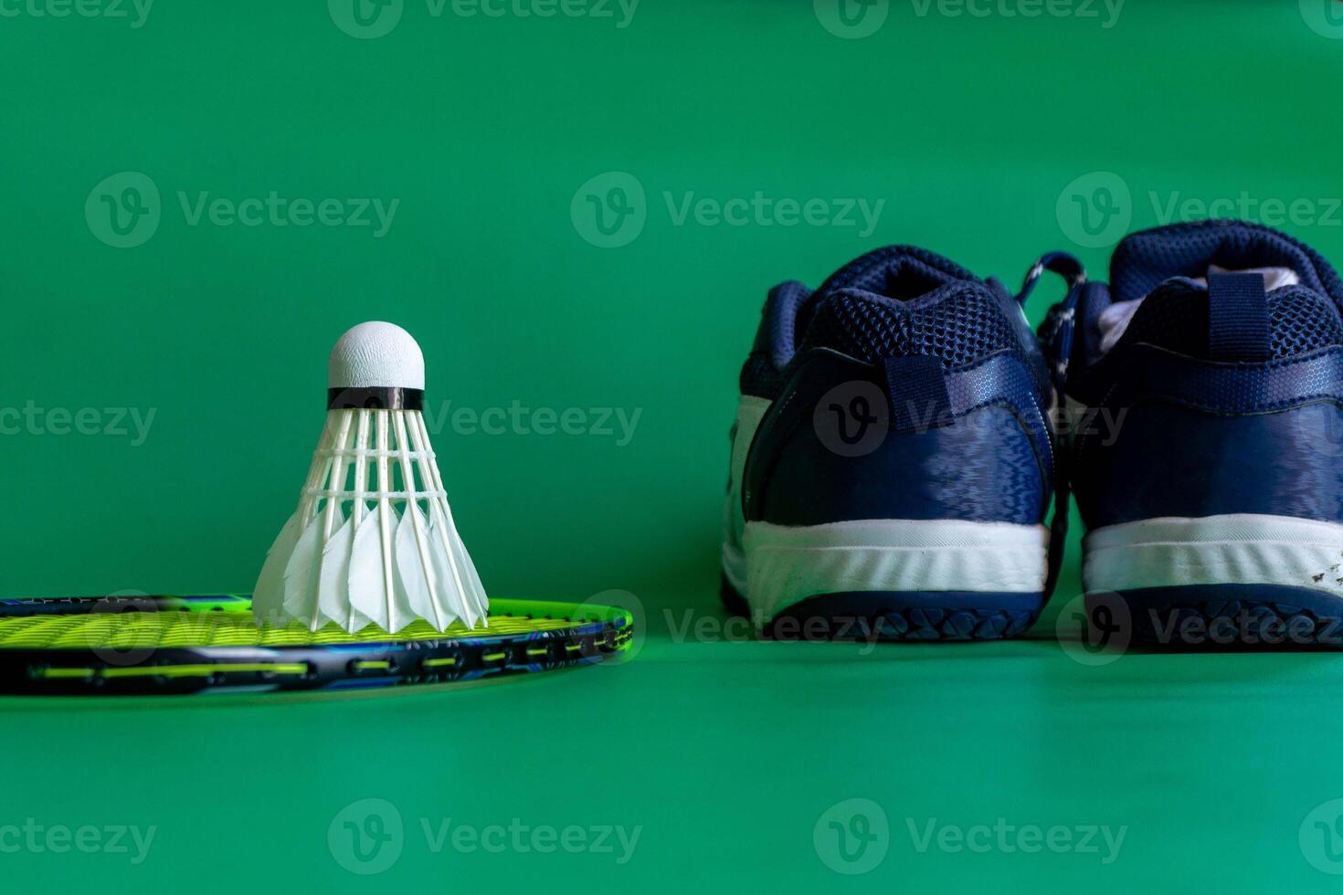 badminton rackets, shuttlecocks, and shoe placed against a vibrant green backdrop, showcasing sports gear photo