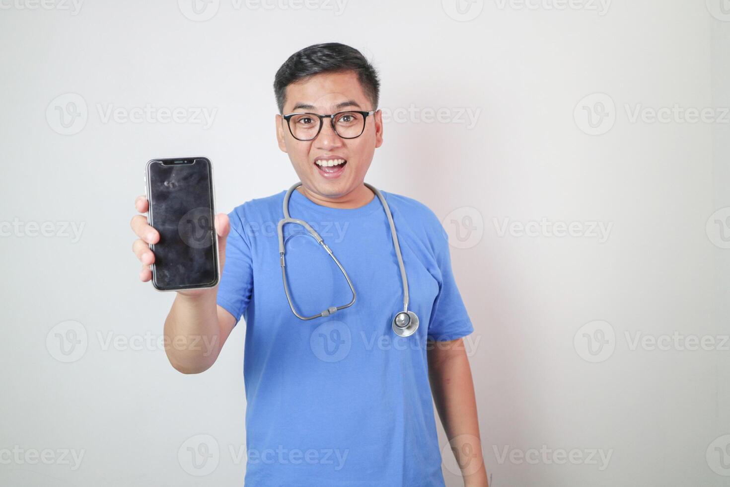 Male doctor in a white coat in a modern clinic reads information from a mobile phone corresponds with colleagues happy and smiles photo