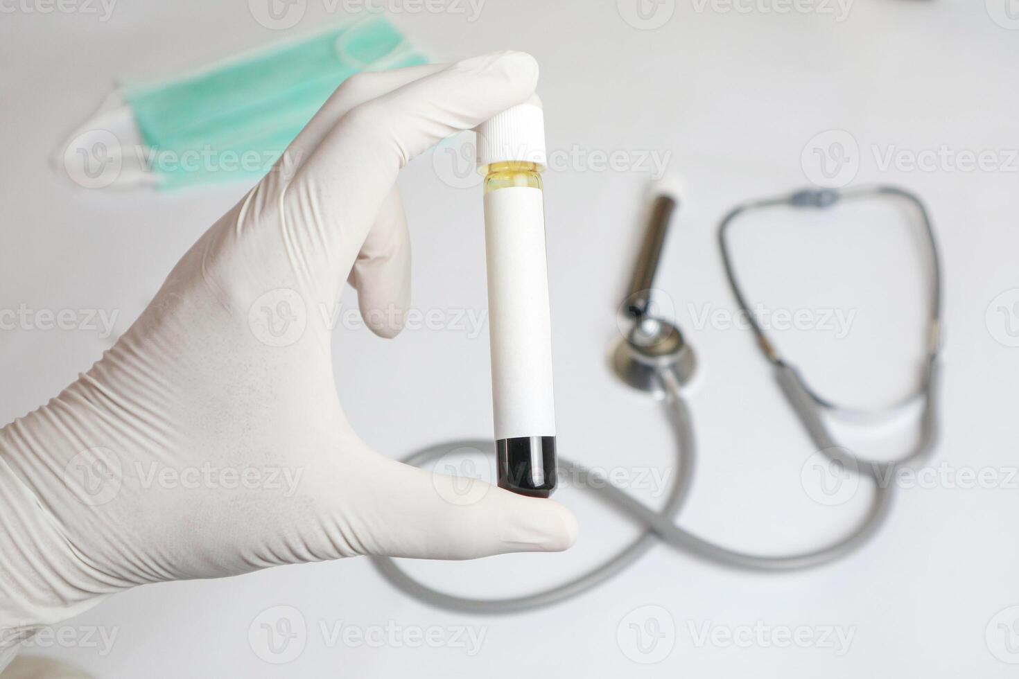 A person is holding a red blood test tube in a blue glove. Concept of caution and precision, as the person is handling a potentially hazardous substance. photo
