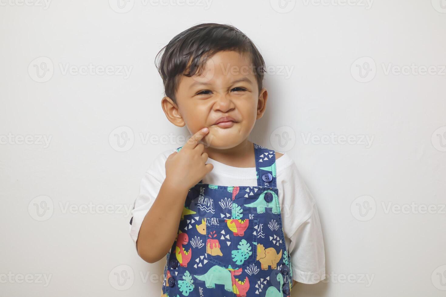 Surprised 2-3 years old Asian boy wearing a t-shirt looking at the camera while covered mouth with hands isolated on white background photo
