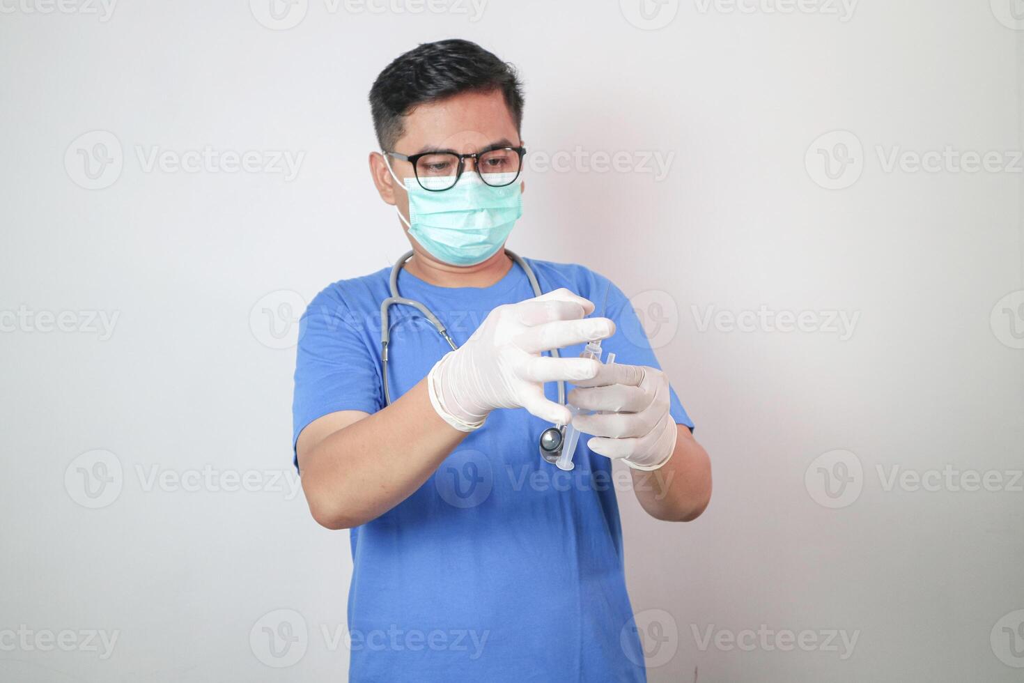 Portrait of an Asian male doctor in uniform on isolated background. He was holding a syringe with an injection. photo