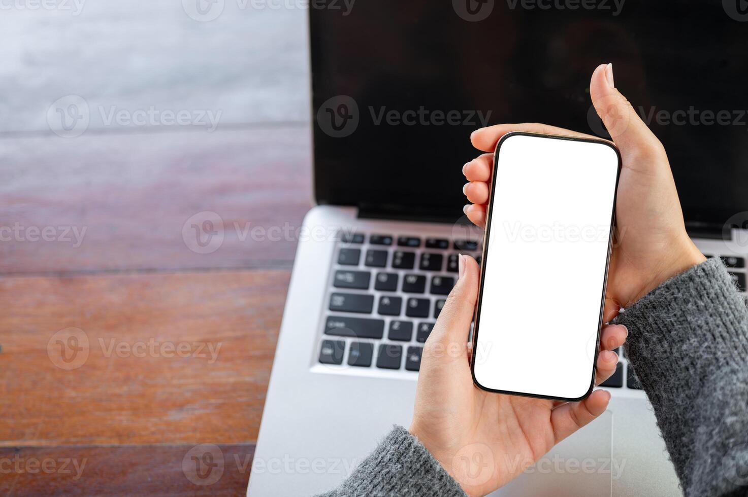 A top view of a woman pointing at a smartphone screen in her hand, using her smartphone at her desk photo