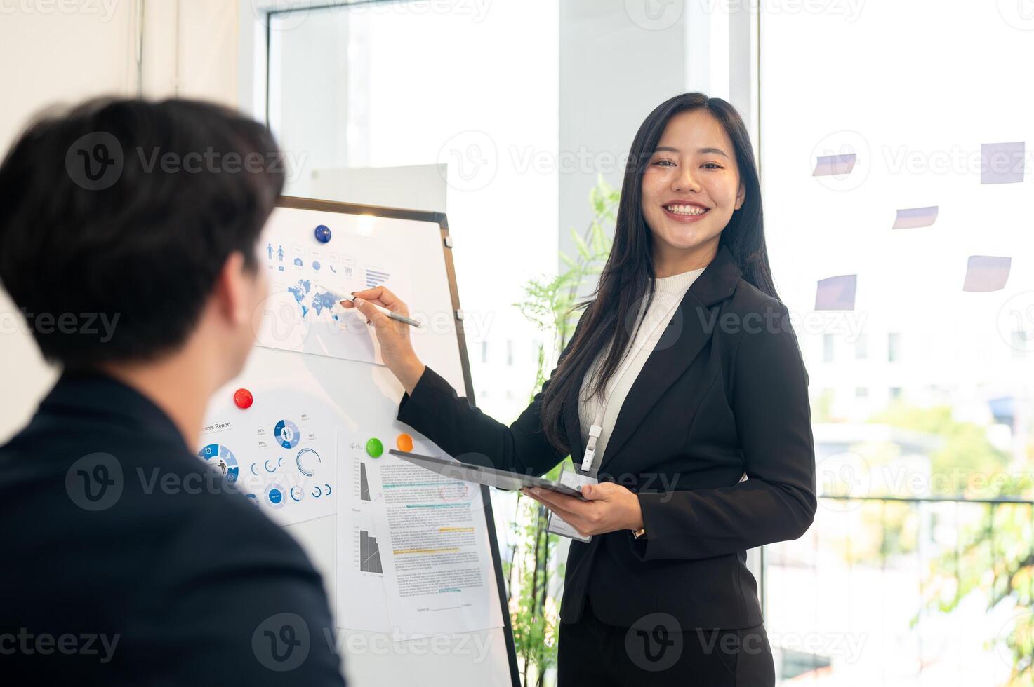 A confident Asian businesswoman stands in front of a board in the meeting and smiling at the camera. photo