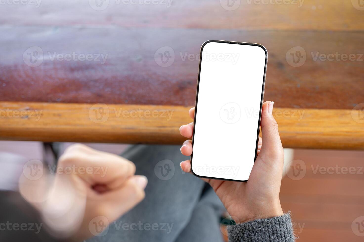 A woman holding a phone and clenching her fist in anger as she reacts to a she is watching. photo