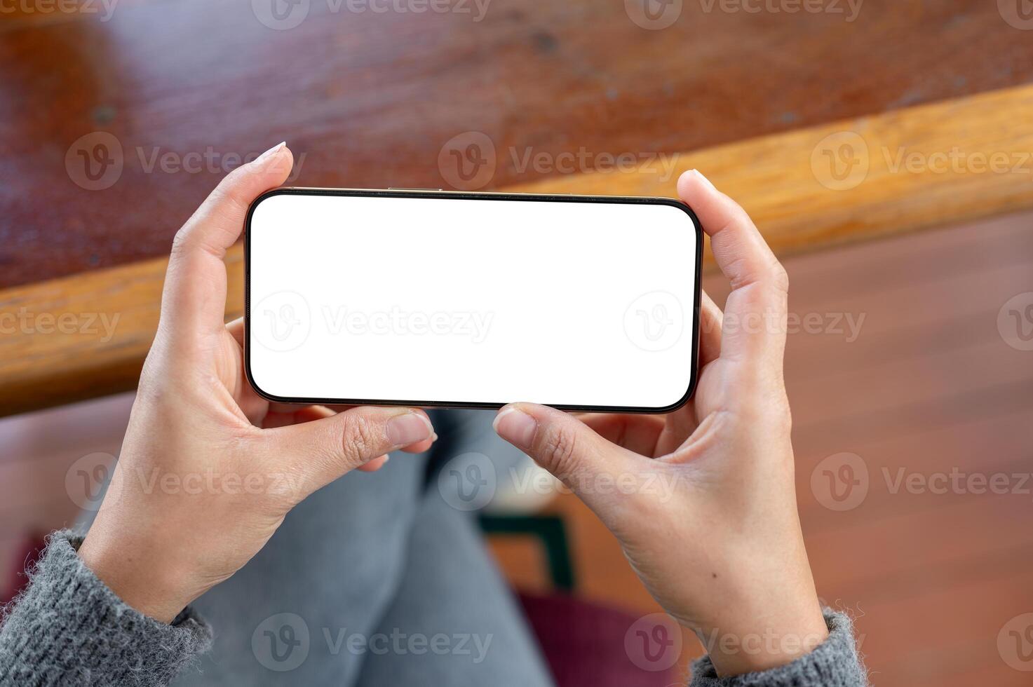 A top view of a woman holds a smartphone in a horizontal positive as she watching videos. photo