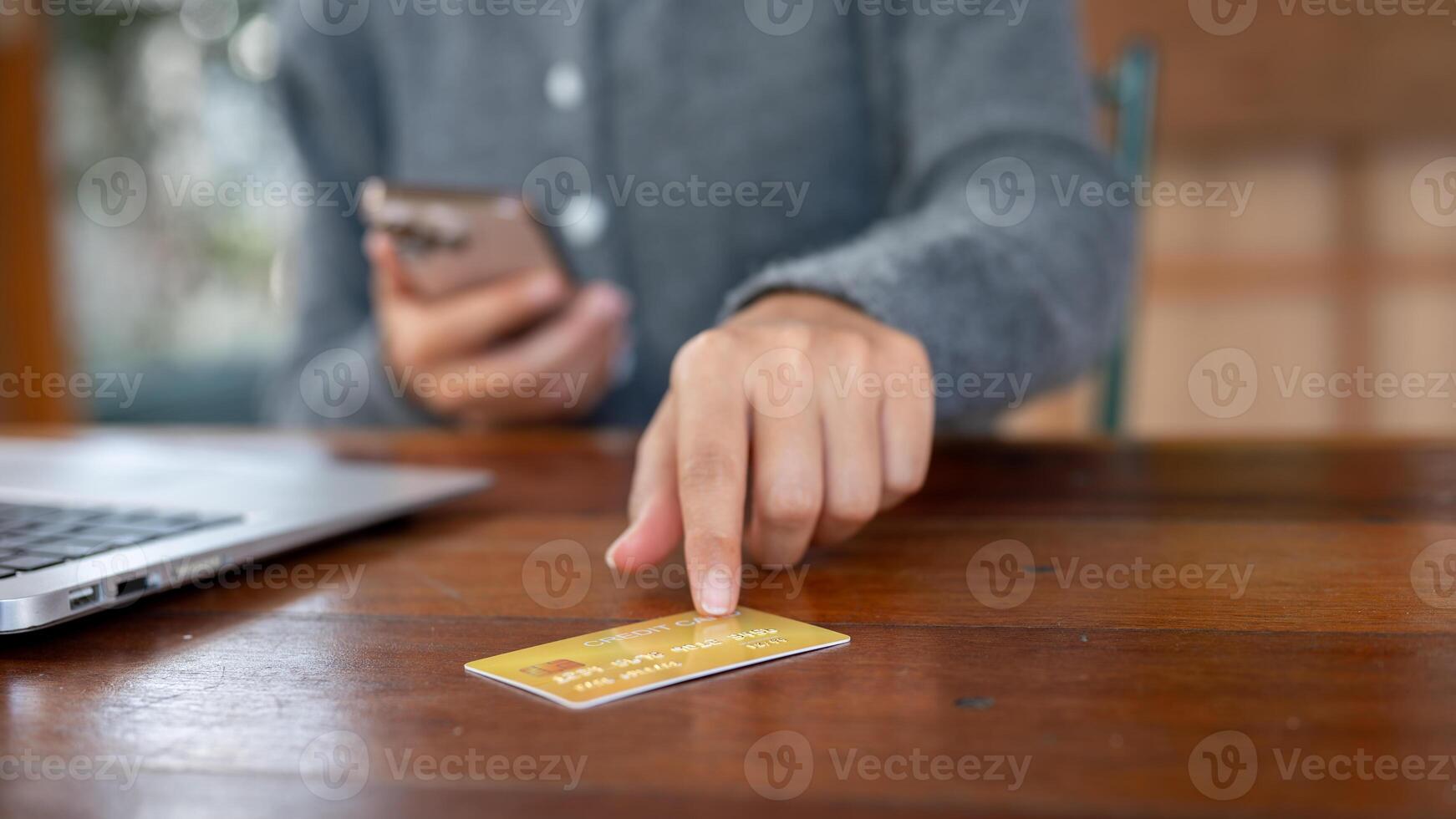 A close-up of a woman pointing at a credit card on a table, shopping online, online payment. photo