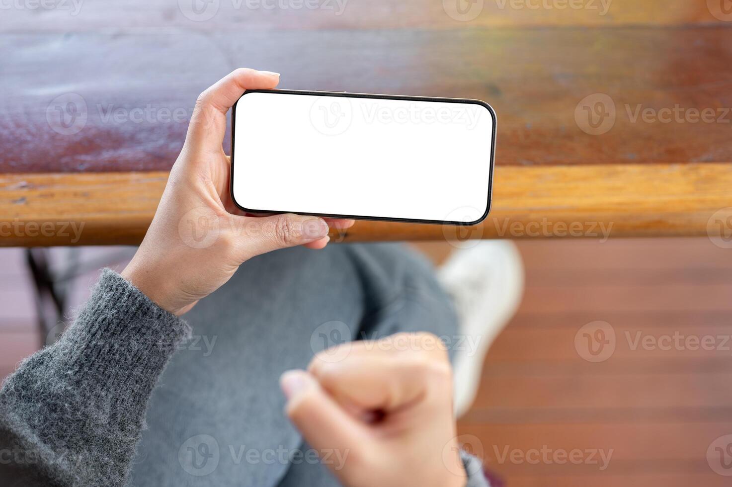 A woman holding a phone and clenching her fist in excite as she reacts to a she is watching. photo