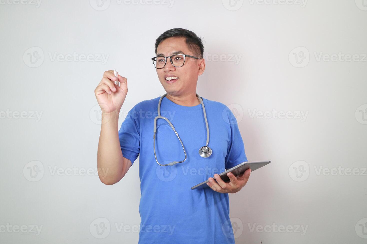 Young and handsome smart Asian doctor wearing surgical hygiene protective mask isolated on white background and holding mockup blank copy space screen tablet computer in hand. Idea for medical people. photo