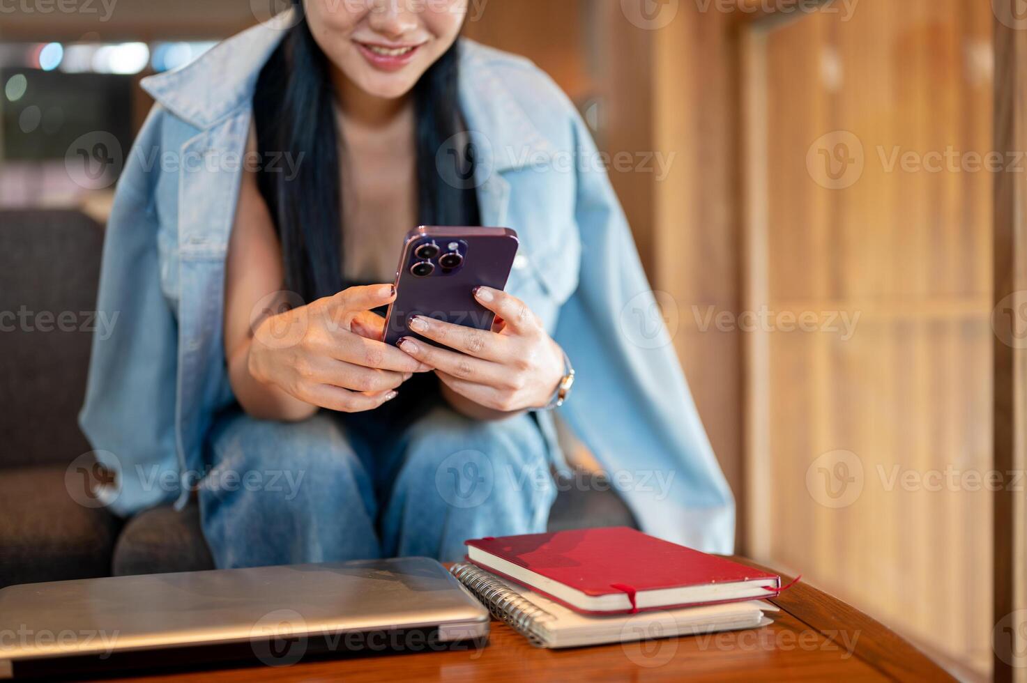 A smiling Asian woman sitting in a coffee shop, enjoying using social media on her smartphone. photo
