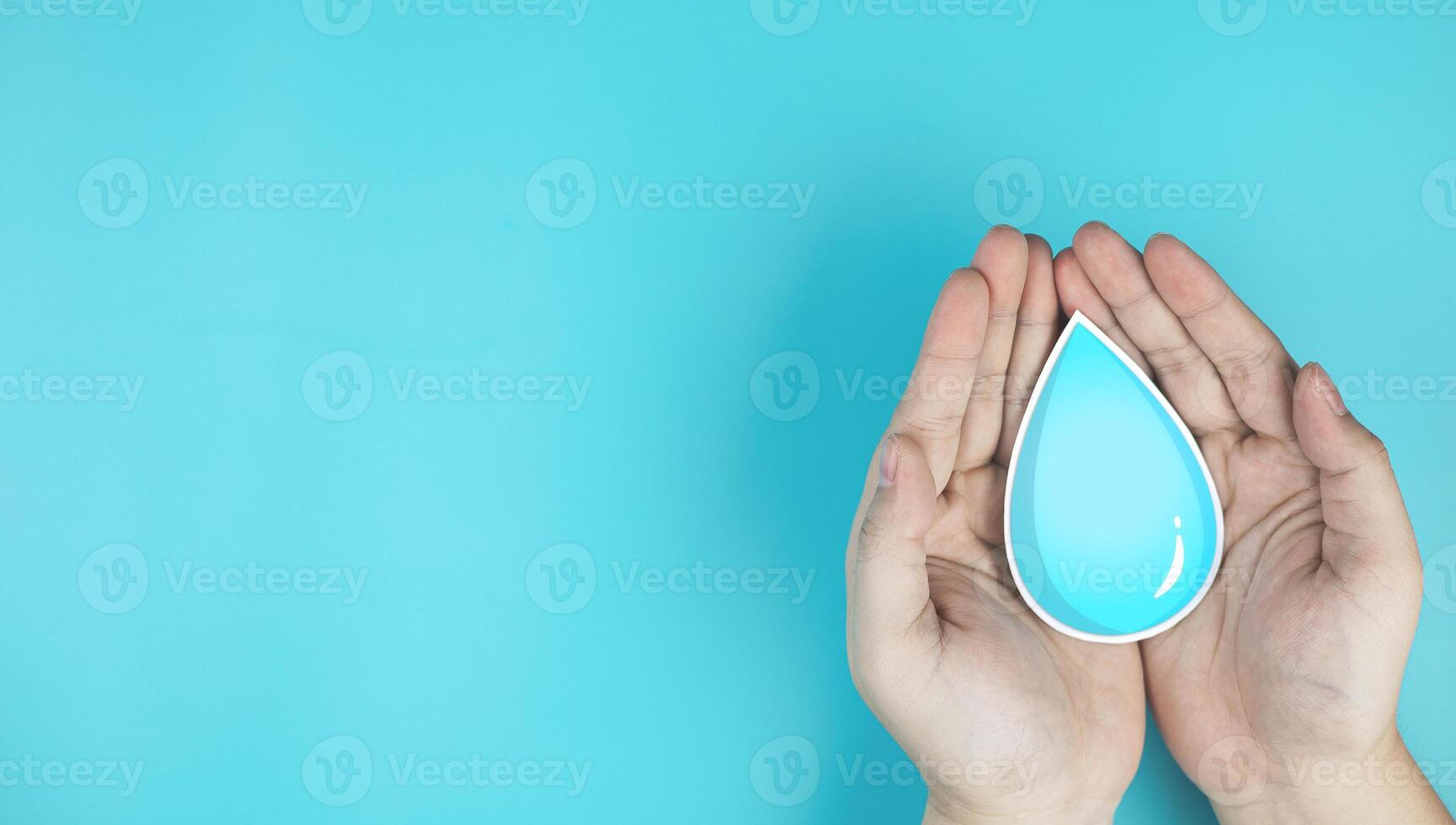 Water drops in hand on blue background with copy space. Concepts of saving water, World Day for Water, conserving environmental resources, and treating wastewater to clean water sources. photo