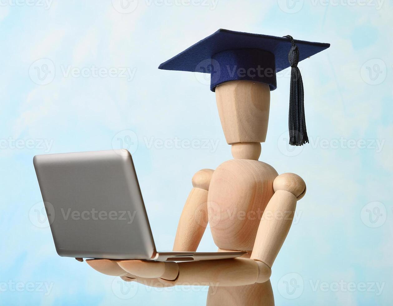 Wooden Graduate Figurine and Laptop Seen from Above photo