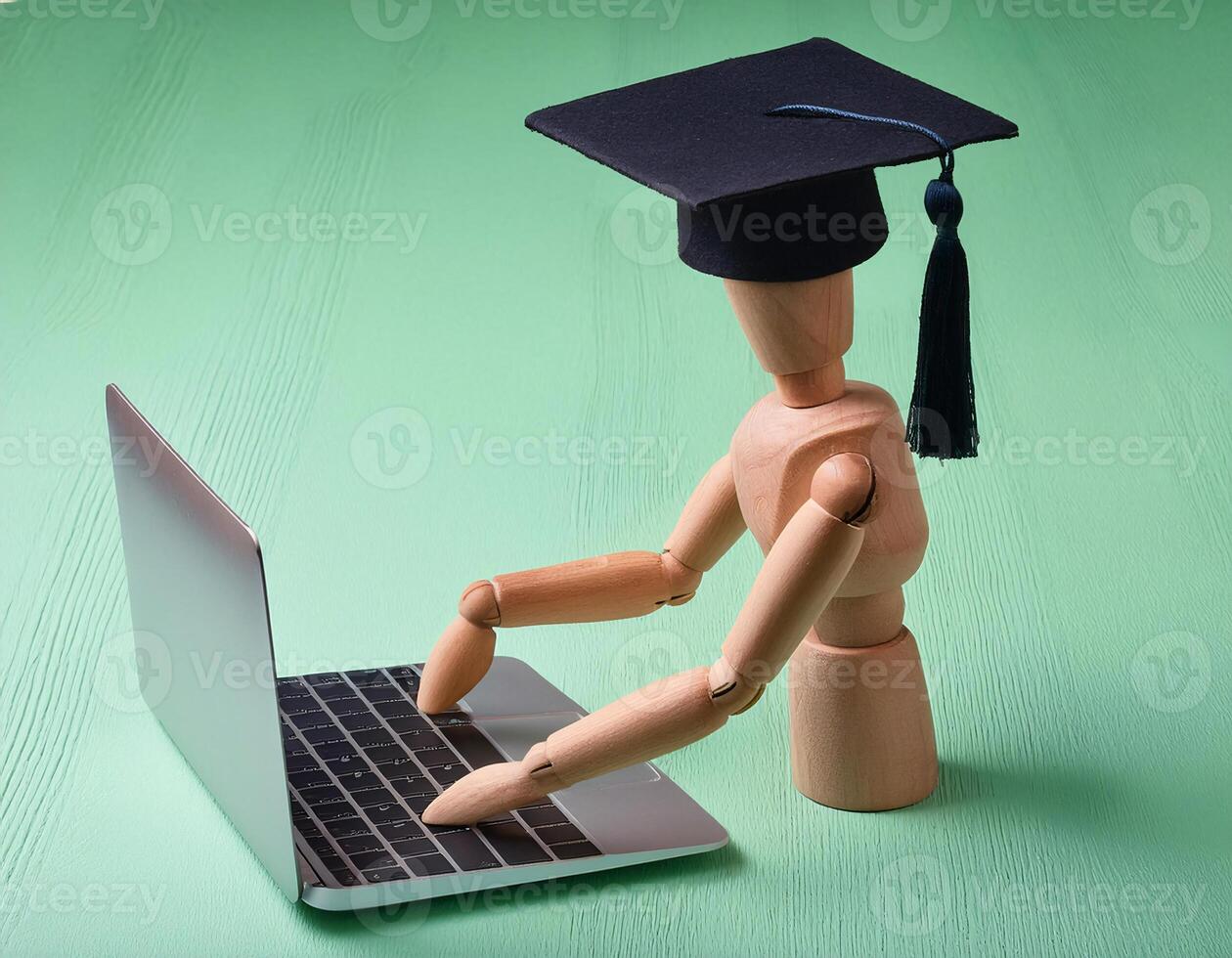 Top View of Wooden Figurine Wearing Graduation Cap with Laptop photo