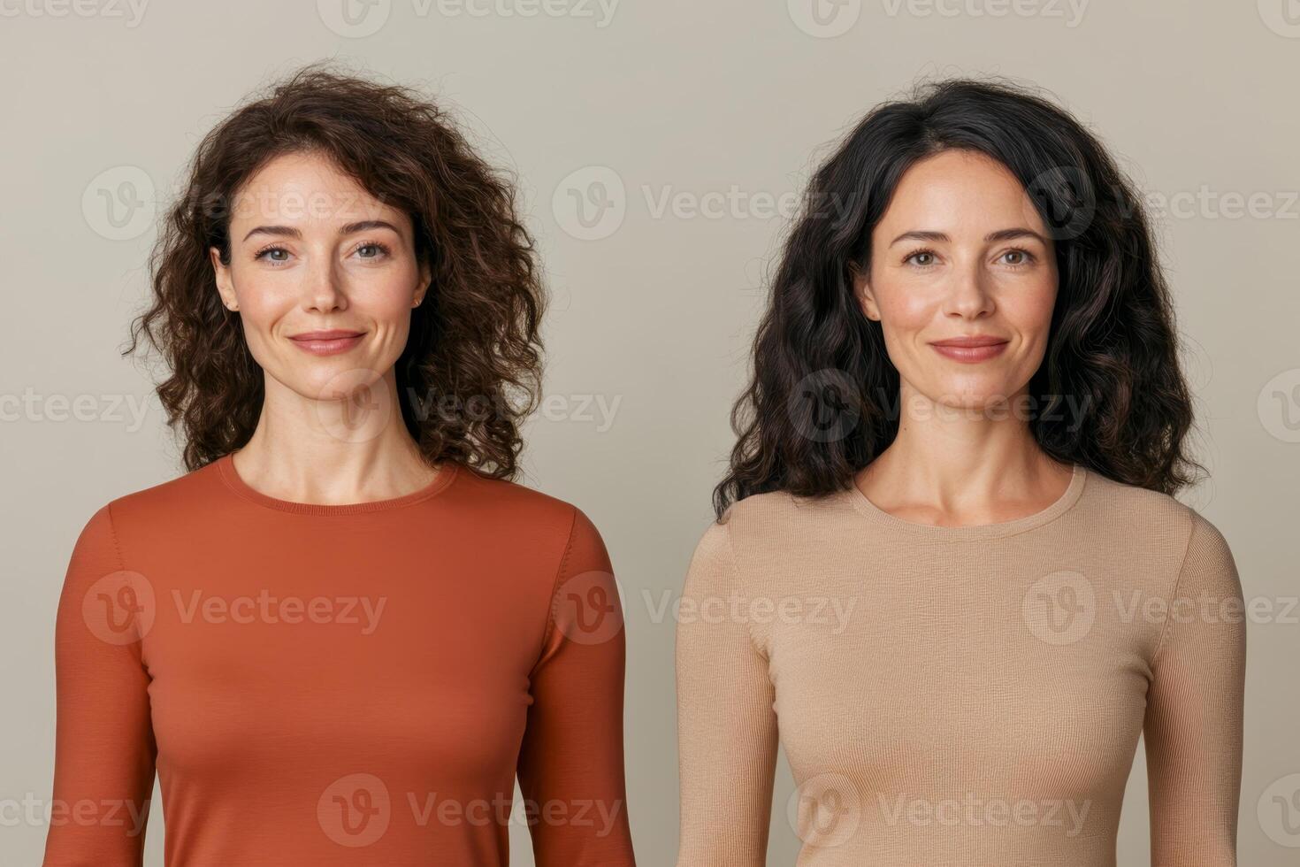 Two women with curly hair showcase different sweater styles in a neutral studio setting during daylight photo