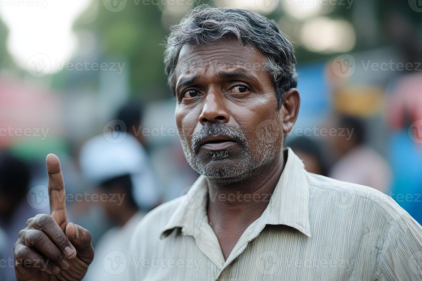 Man engaged in animated discussion while standing in a crowded outdoor area during a warm afternoon photo