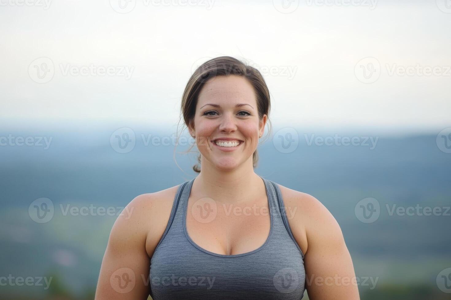 Strong woman smiles confidently against a scenic outdoor backdrop during daylight photo