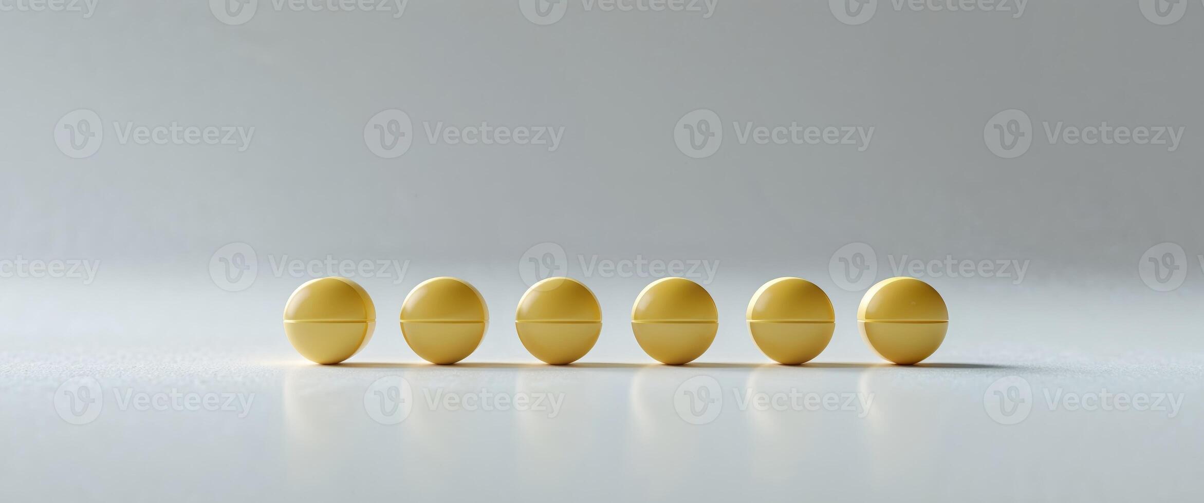 Four yellow pills are lined up on a white surface photo