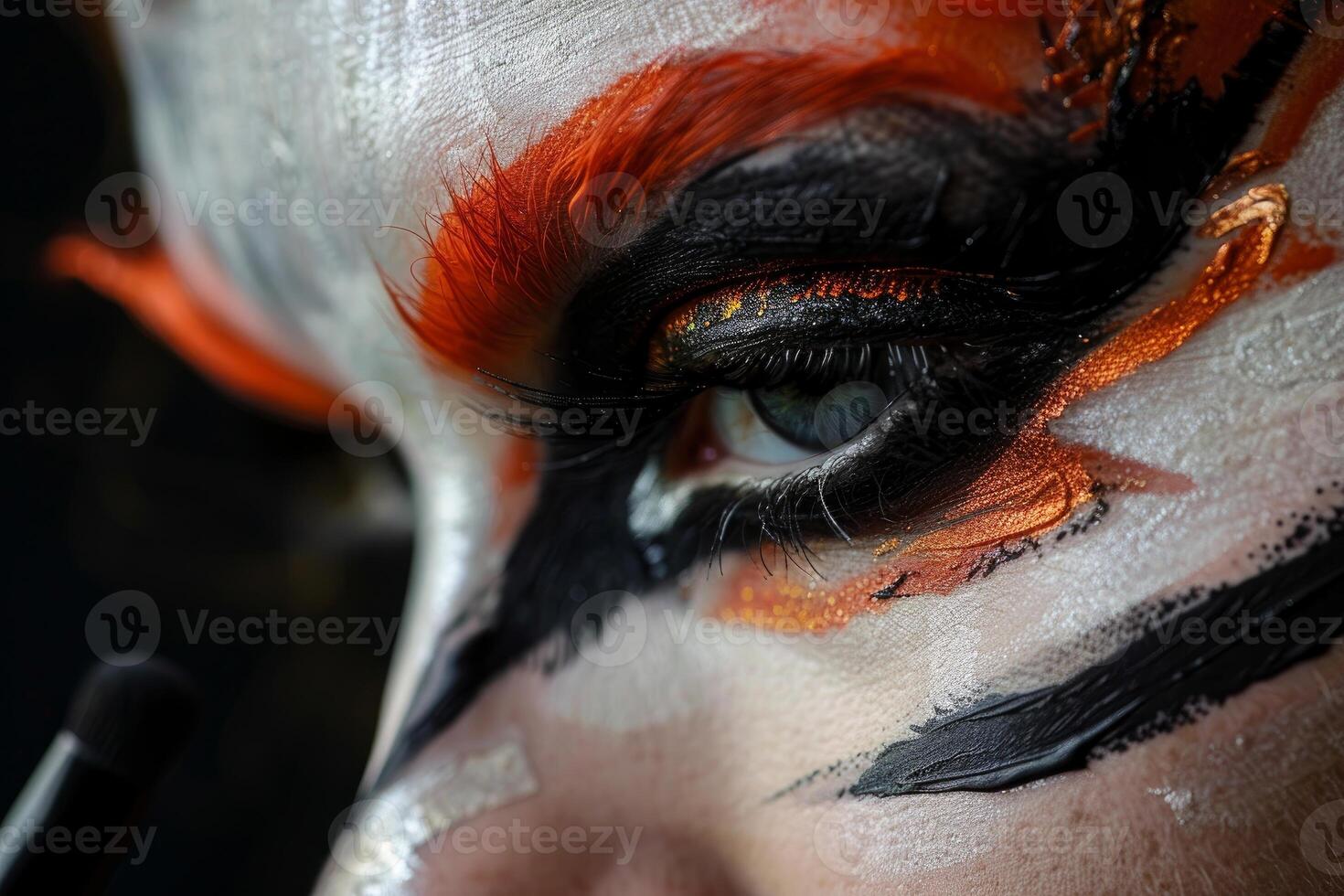 Makeup artist applying fantasy makeup with orange and black tones photo