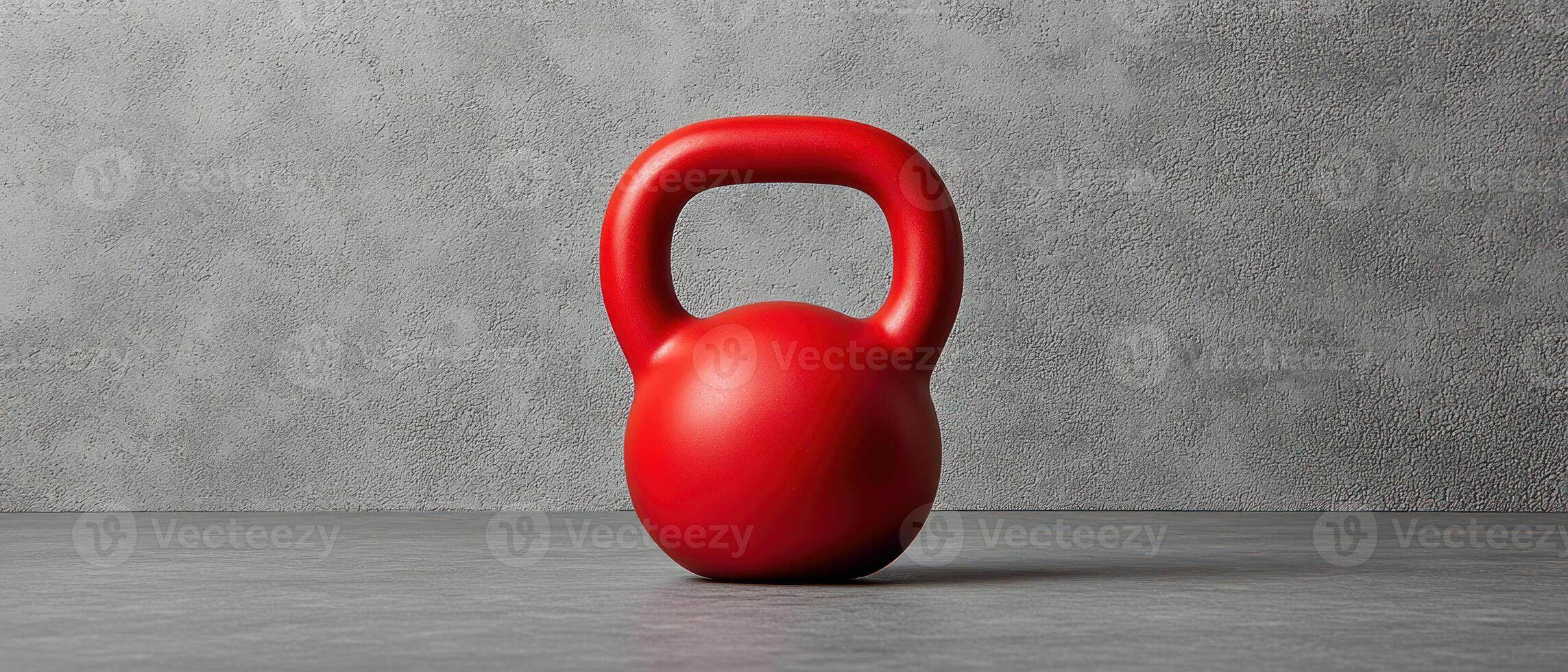 A vibrant red kettlebell on a textured gray background for fitness enthusiasts. photo
