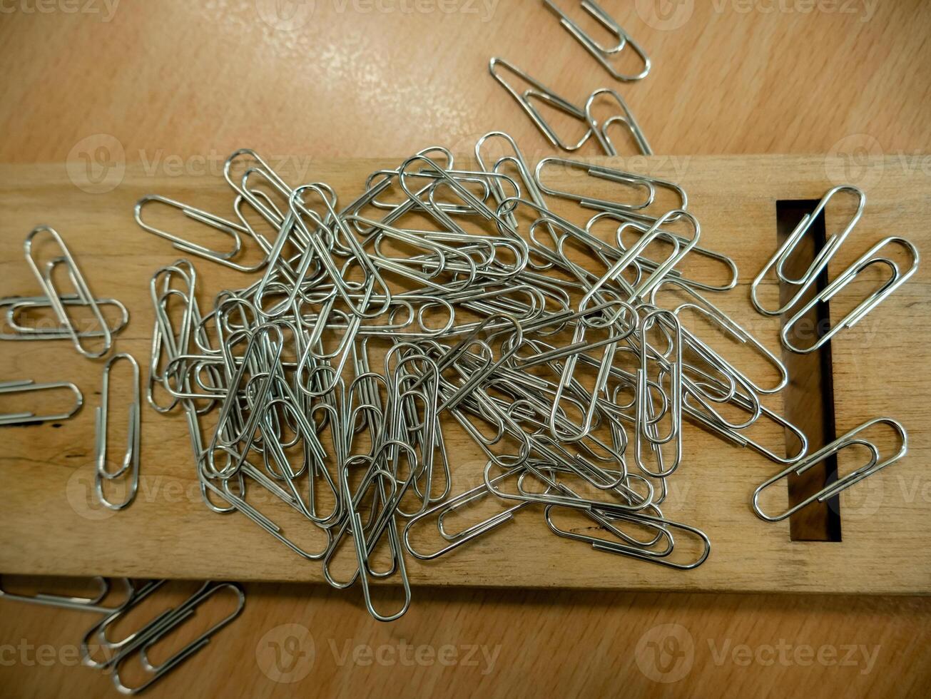 stack of shiny paper clips on the small wooden board photo