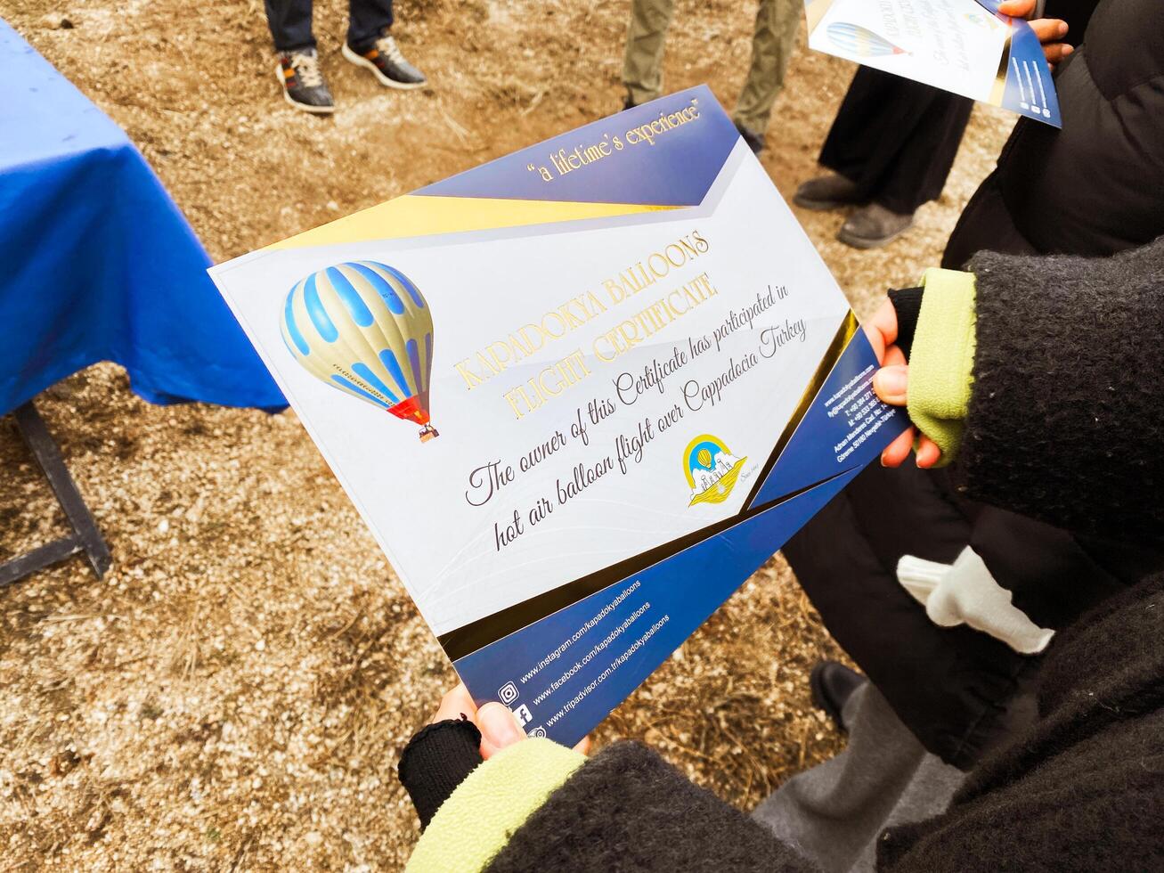 Goreme, Turkey , 2024 - tourist woman pose hold certificate by Hot air balloon after flight in Cappadocia. Post flight and certificate ceremony. Kapadokya balloons flight attraction photo