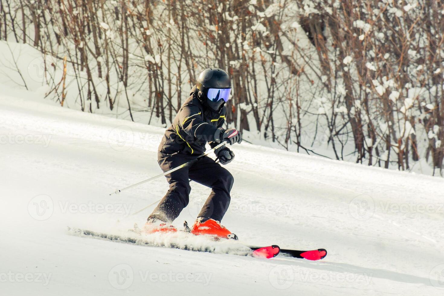 Dynamic picture of male skier in black outfit on the piste ski downhill fast motion in Alps. Active winter holidays, skiing downhill in overcast day. Ski rides on the track with swirls of fresh snow photo