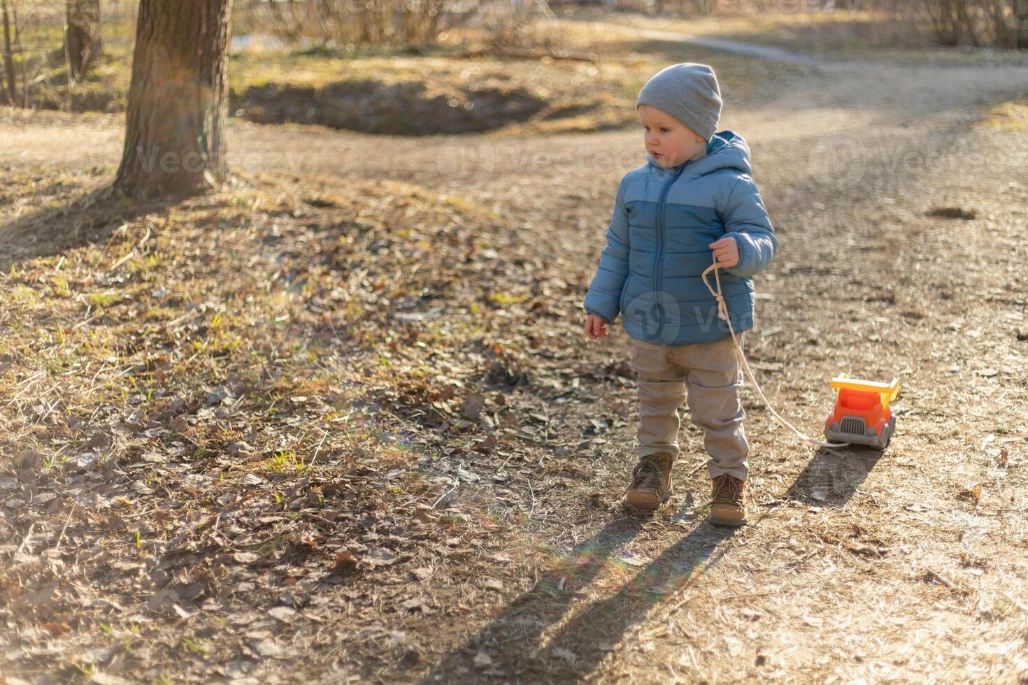 Happy baby child outdoor. Little toddler boy with toy car having fun on walk in park. Baby son smiling playing outdoor. Little child resting walking in nature. Little toddler child having fun on walk photo