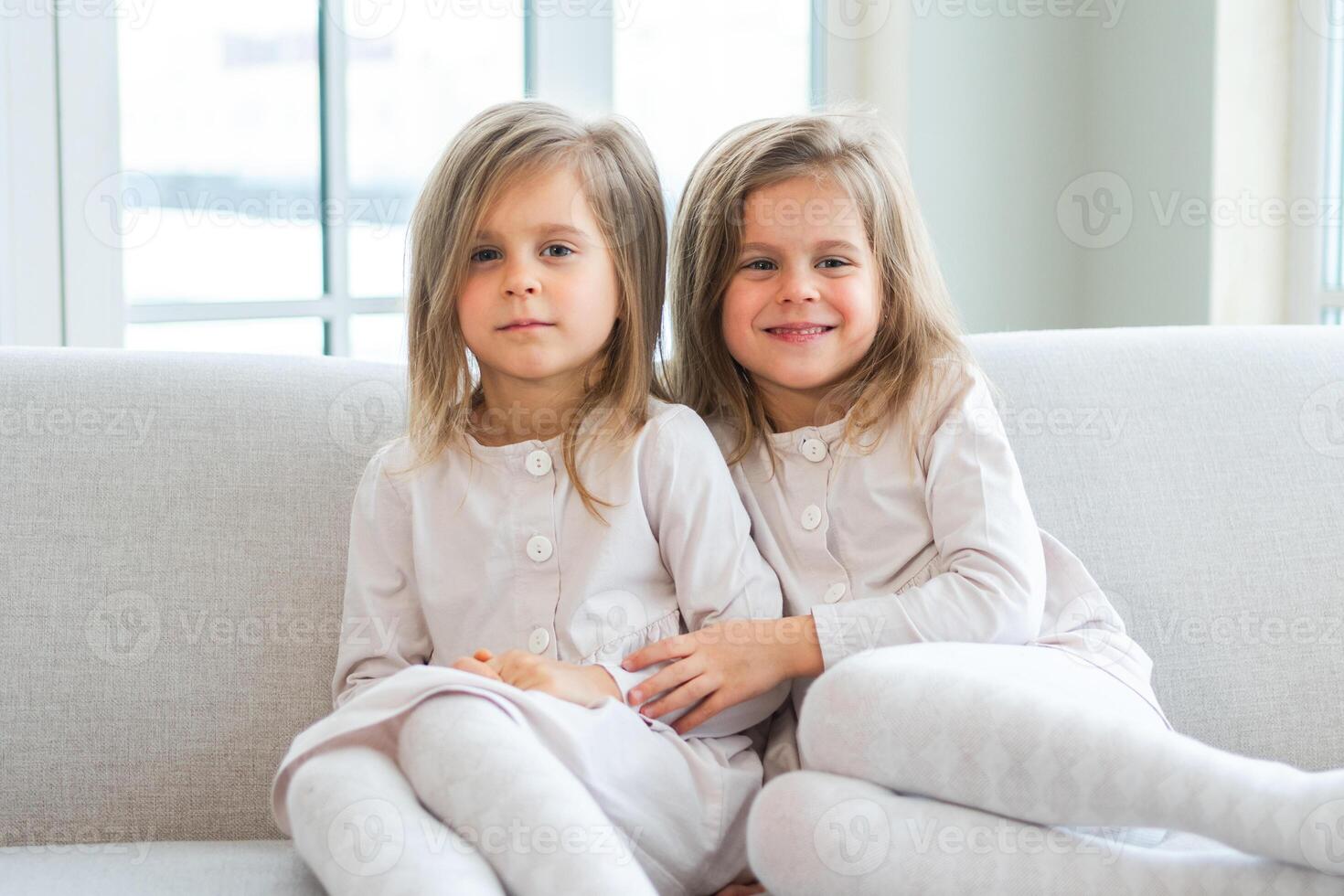 Happy family sisterly love. Two funny little twin sisters girls hugging with love care playing together at home indoors. Happy children lifestyle. Identical twin girls hugs. Girls friendship and youth photo