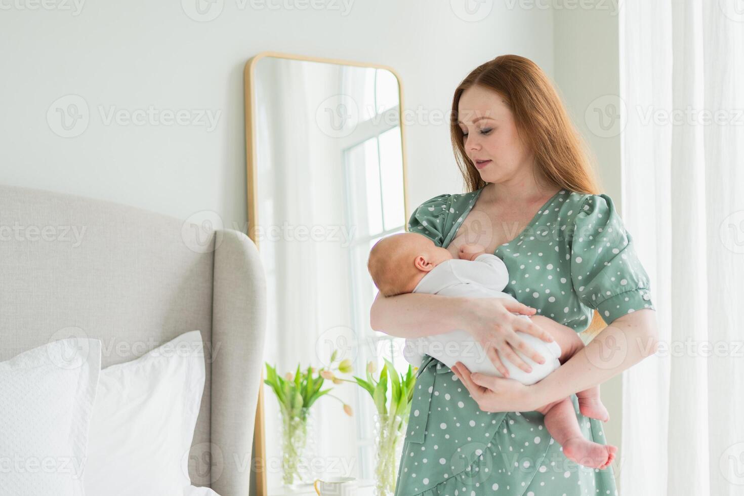 Happy family at home. Mother breastfeeding baby for health nutrition wellness. Mom nursing feeding her newborn child milk at home. Woman infant girl in white bedroom Mother hugs baby with love care photo
