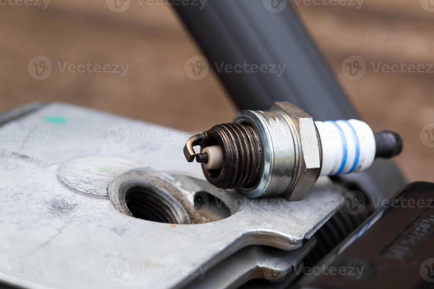Spark plug unscrewed from the cylinder of the combustion chamber of a two-stroke engine. Replacement and malfunction of the ignition system, macro photo
