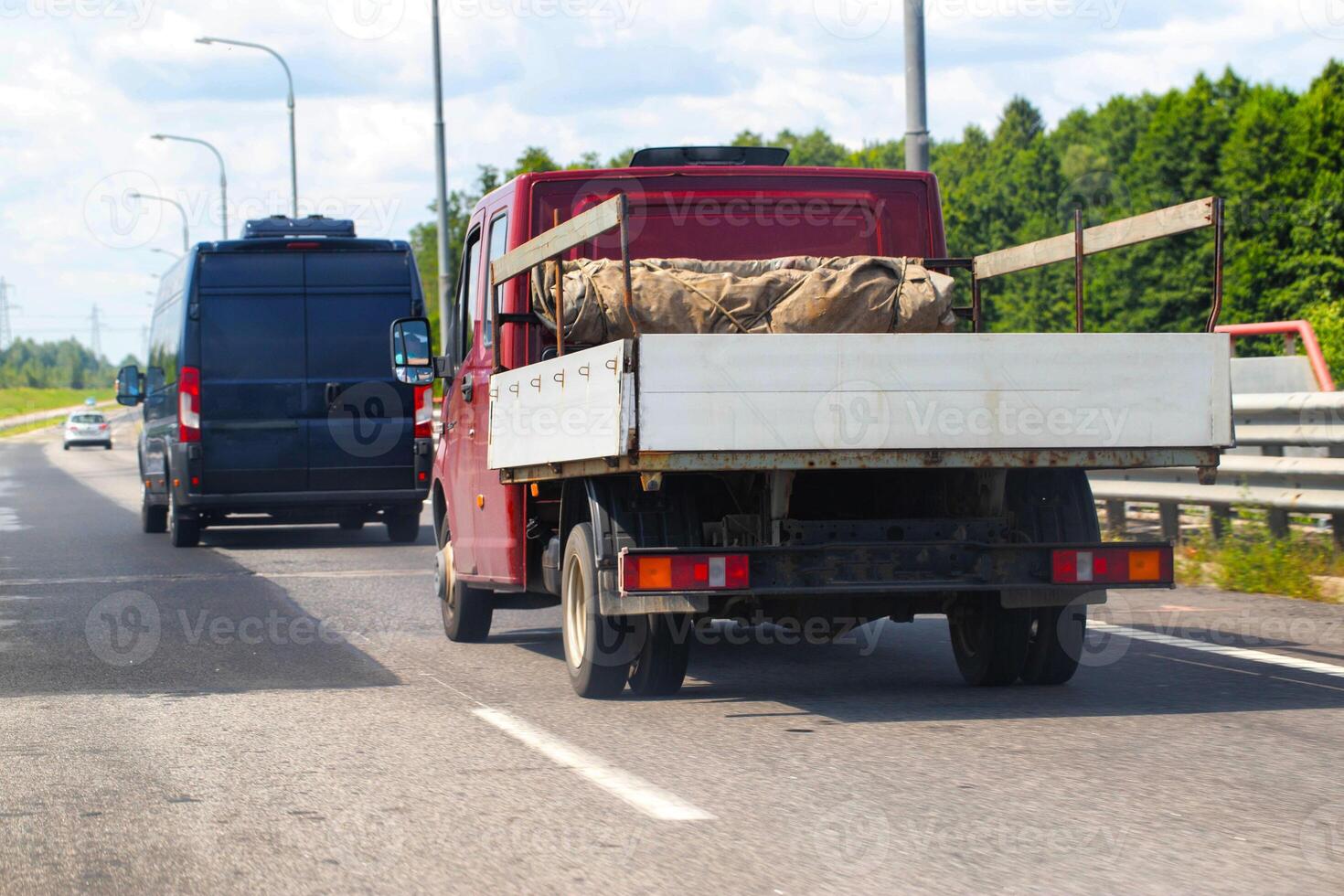 An open flatbed truck drives on a highway in summer. Transportation of goods up to 5 tons. Rental of trucks for regional and international transportation. Copy space for text photo