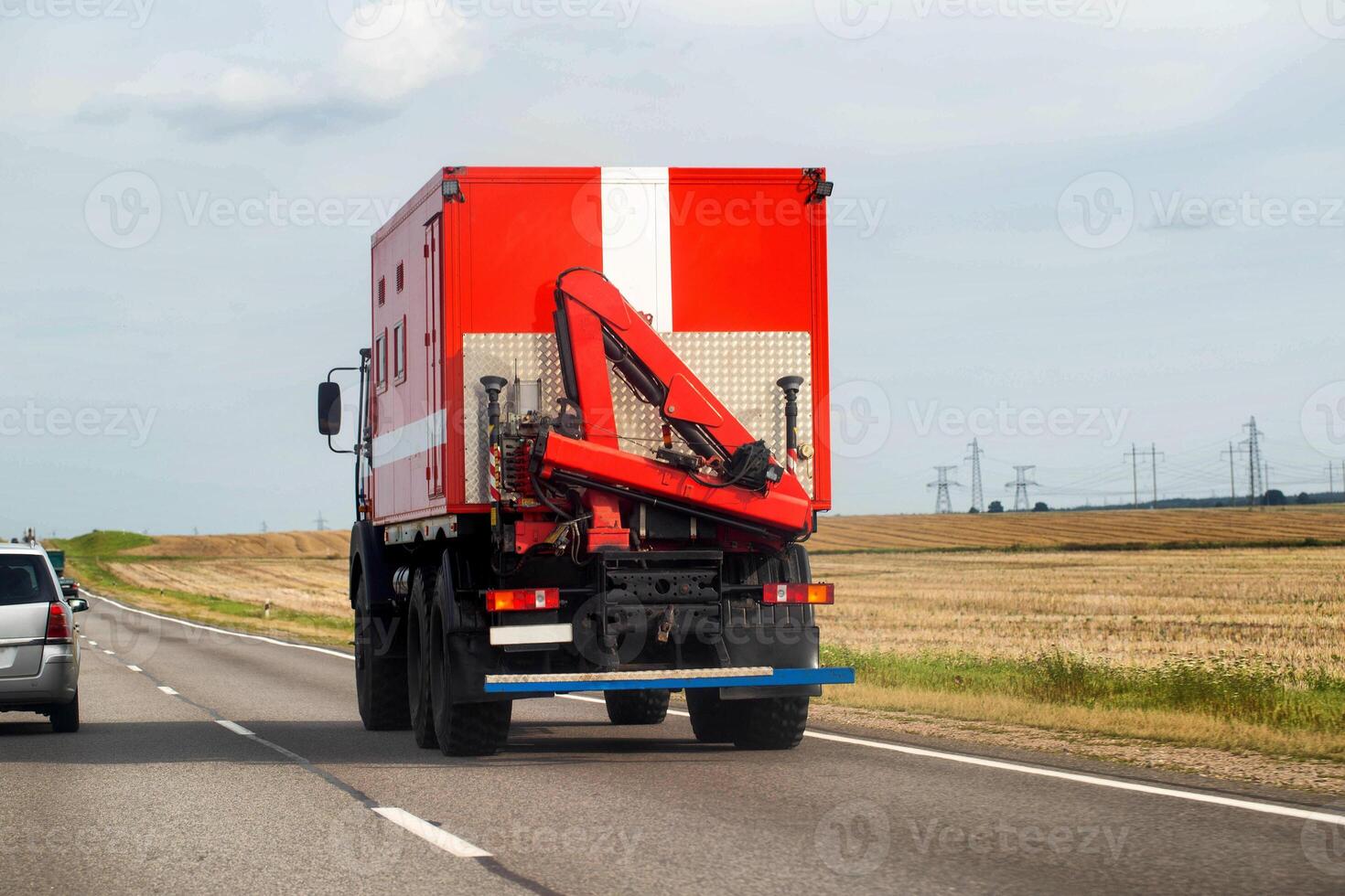 A special fire truck with a manipulator crane driving along a highway in summer, copy space for text photo
